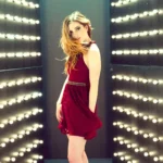 Sydney Sierota wearing a red dress posing inside a tunnel of glowing lights with cinematic reflections and elegant atmosphere wallpaper