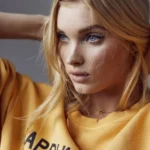 Close-up portrait of blonde model with blue eyes wearing yellow sweatshirt in soft natural lighting wallpaper