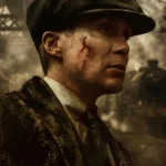 Tommy Shelby in Peaky Blinders with scar on face in smoky industrial train yard cinematic wallpaper