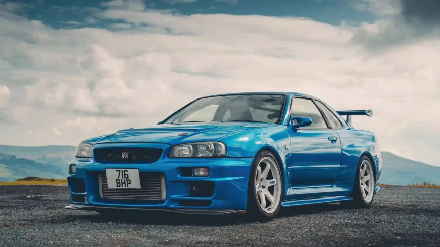 Blue Nissan Skyline GT-R R34 parked on scenic road with dramatic cloudy sky wallpaper