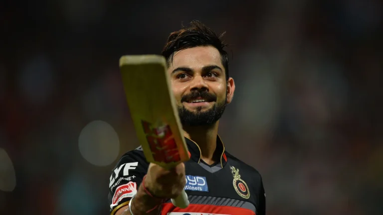 Virat Kohli holding a cricket bat in RCB jersey during a stadium celebration wallpaper