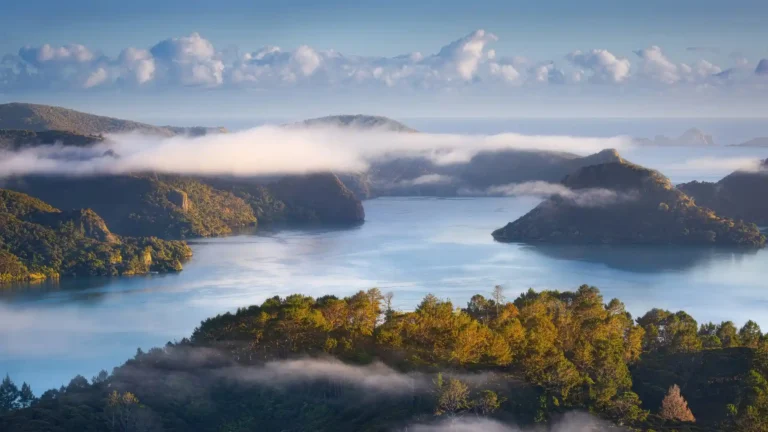 Misty coastal landscape of Whangaroa Northland New Zealand with calm ocean and green hills wallpaper