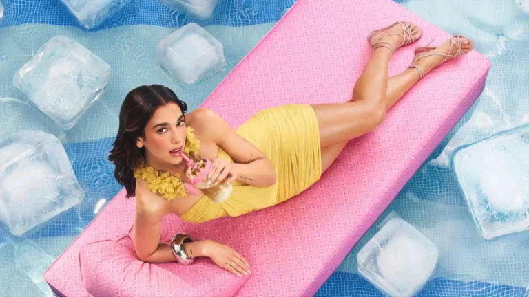 Celebrity relaxing on a pink pool float surrounded by water and ice cubes in a colorful summer fashion photoshoot wallpaper