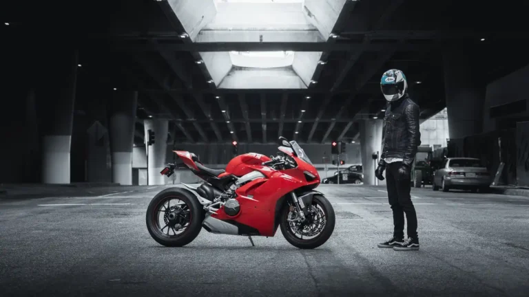 Red Ducati Panigale superbike with rider standing beneath a modern urban overpass wallpaper