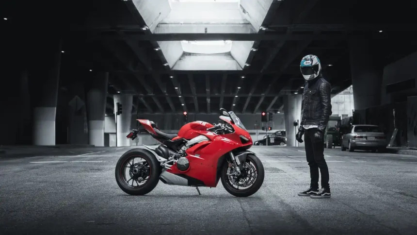 Red Ducati Panigale superbike with rider standing beneath a modern urban overpass wallpaper