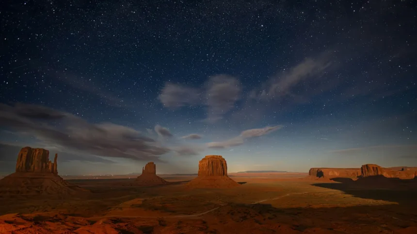 Monument Valley desert buttes beneath a star-filled night sky panorama wallpaper