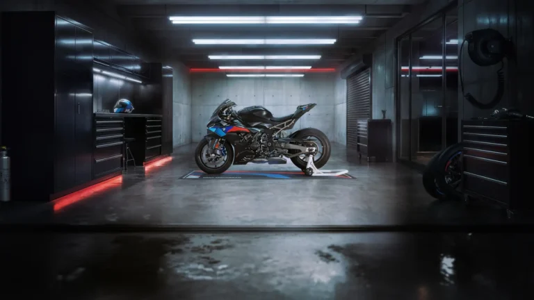 BMW S1000RR M Sport superbike with iconic M colors parked inside a cinematic dark garage with red and white lighting wallpaper.