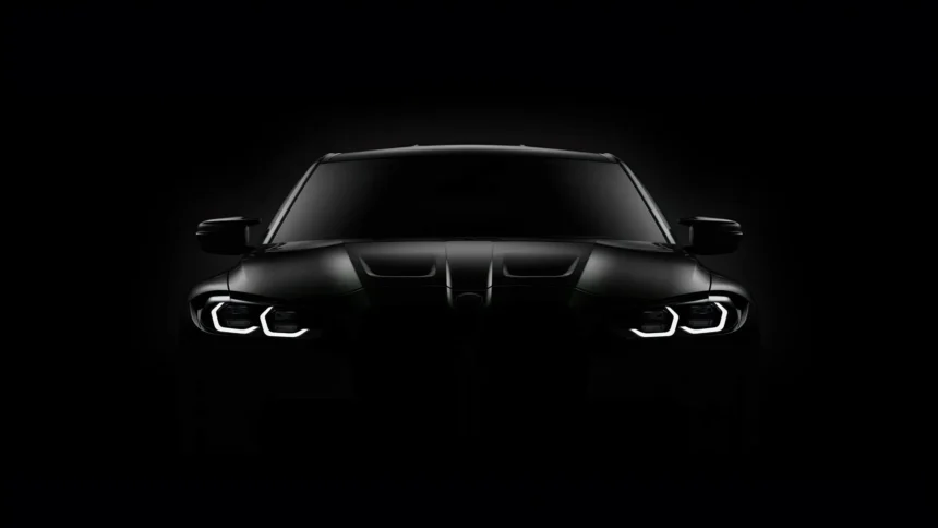 BMW M3 Competition Black Edition viewed from the front, featuring a matte black exterior, illuminated white LED headlights, sculpted hood, and dark kidney grille against a pure black background wallpaper.