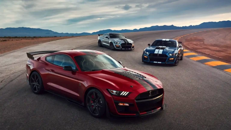 Ford Mustang Shelby GT500 muscle cars in red, blue and silver posed together on a desert racetrack wallpaper.